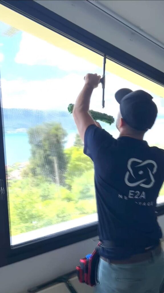 Agent d'entretien E2A Nettoyage en train de laver les vitres avec vue sur le lac d'Annecy
