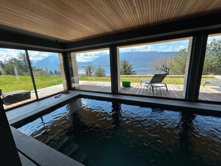 Nettoyage des baies vitrées d'une piscine intérieure avec vue sur le lac